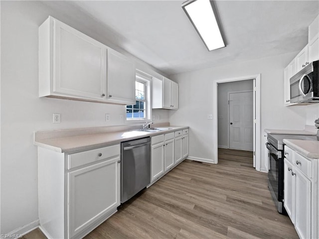 kitchen with light wood finished floors, white cabinets, appliances with stainless steel finishes, and a sink