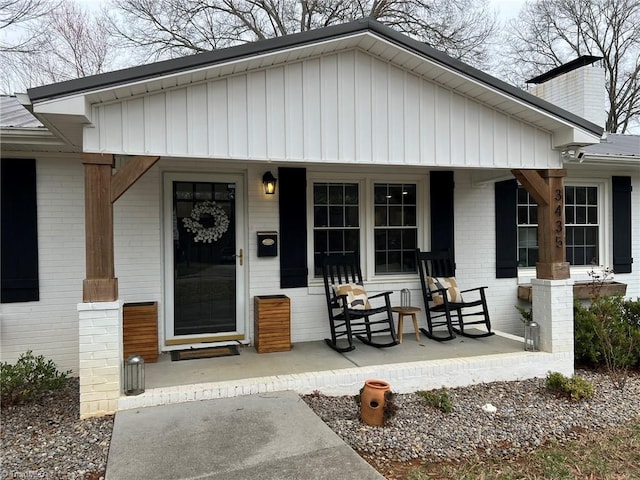 view of front of property with brick siding, a porch, metal roof, and a chimney