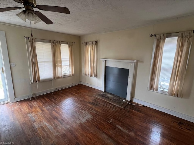 unfurnished living room featuring ceiling fan, dark wood-type flooring, and a textured ceiling