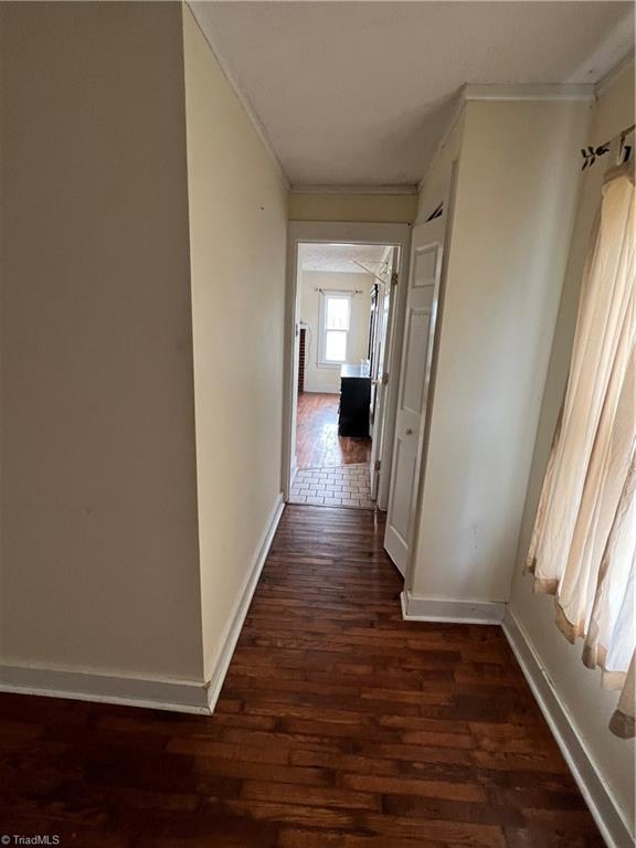 hall featuring crown molding and dark wood-type flooring