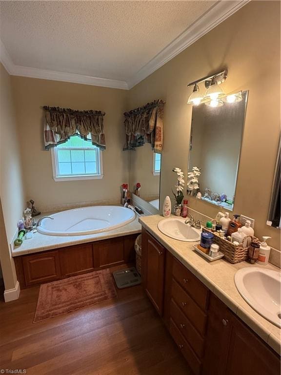 full bathroom with wood finished floors, a textured ceiling, a garden tub, crown molding, and double vanity