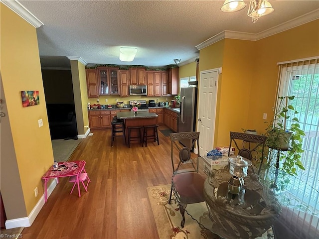 dining area with wood finished floors, crown molding, baseboards, and a textured ceiling