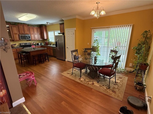 dining space featuring wood finished floors, a textured ceiling, a chandelier, and crown molding