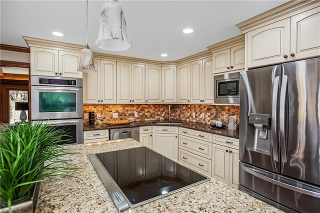 kitchen featuring appliances with stainless steel finishes, decorative light fixtures, dark stone countertops, and cream cabinetry