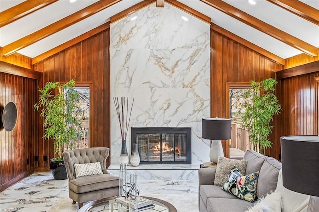 living room with a premium fireplace, vaulted ceiling with beams, and wood walls