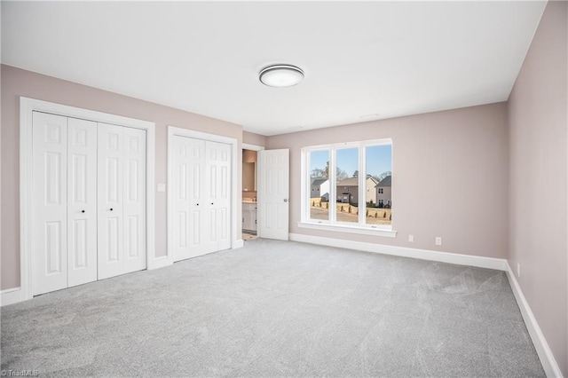 unfurnished bedroom featuring multiple closets and carpet