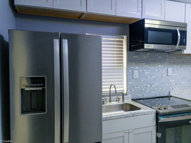 kitchen featuring white cabinetry, appliances with stainless steel finishes, sink, and backsplash