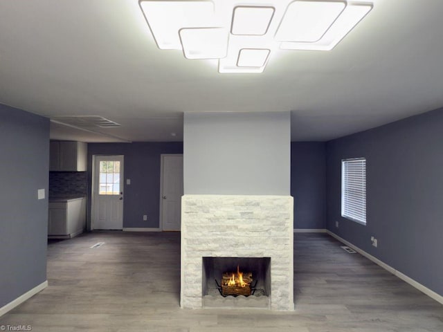 unfurnished living room with wood-type flooring and a stone fireplace