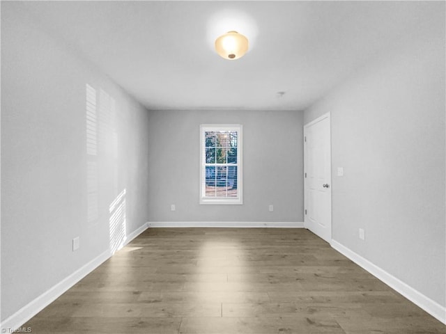 spare room with baseboards and dark wood-style floors