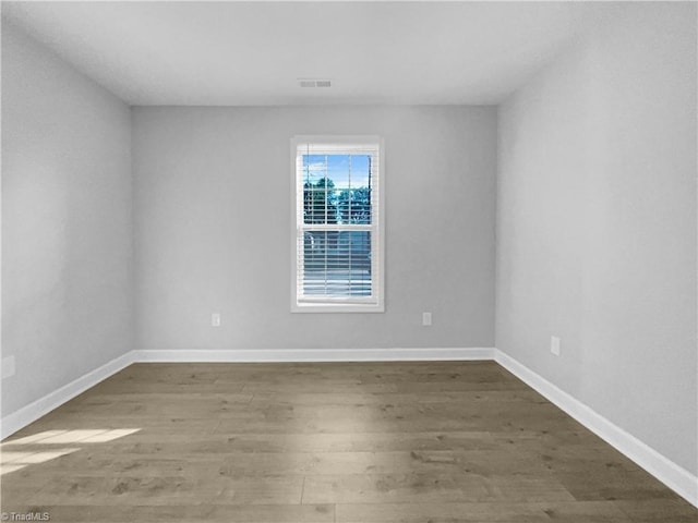 spare room with visible vents, wood finished floors, and baseboards