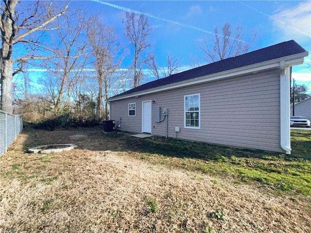 rear view of property with central AC unit and fence