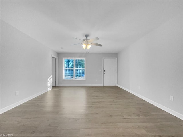 unfurnished living room featuring a ceiling fan, baseboards, and wood finished floors