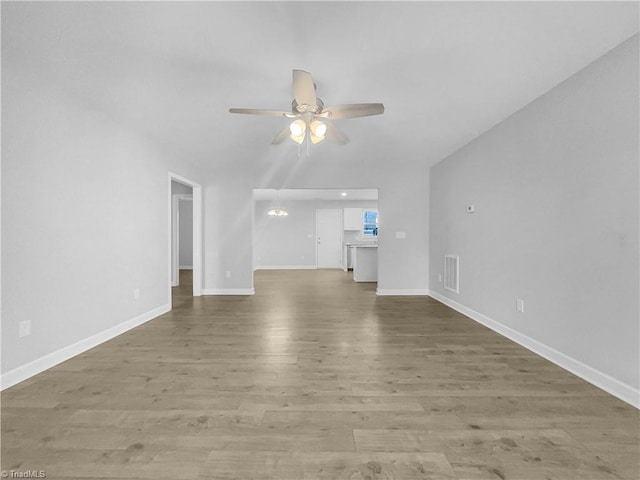 unfurnished living room with ceiling fan with notable chandelier, visible vents, wood finished floors, and baseboards