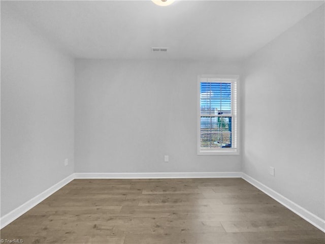 spare room with visible vents, baseboards, and wood finished floors