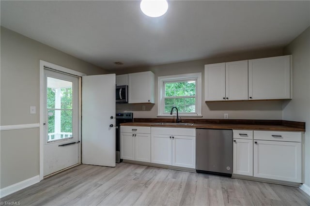 kitchen featuring wooden counters, white cabinets, sink, light hardwood / wood-style floors, and stainless steel appliances