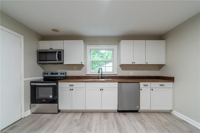 kitchen featuring white cabinets, butcher block countertops, sink, and stainless steel appliances