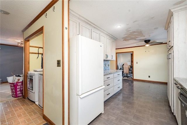 kitchen with white refrigerator, light stone counters, white cabinets, and independent washer and dryer