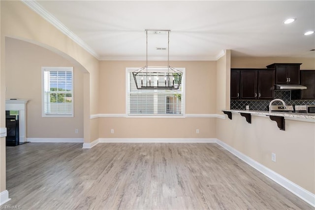2209 Starfall Dr, Colfax, NC 27235 - kitchen with a breakfast bar, light countertops, crown molding, light wood-style floors, and tasteful backsplash