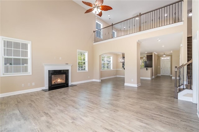2209 Starfall Dr, Colfax, NC 27235 - unfurnished living room with a high ceiling, ceiling fan, stairs, a fireplace, and wood finished floors