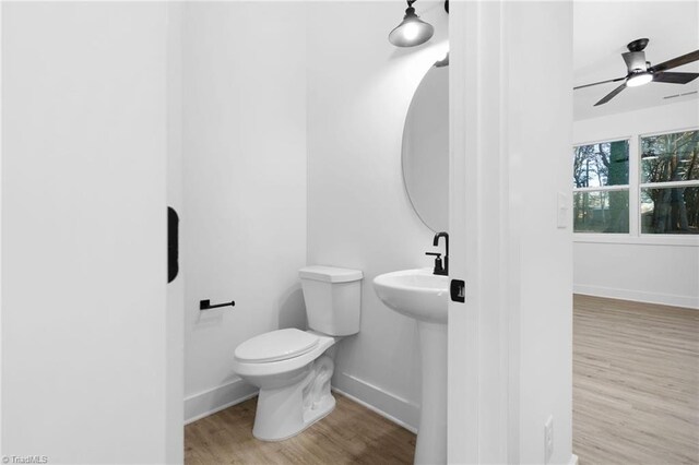 bathroom with baseboards, a ceiling fan, toilet, wood finished floors, and a sink