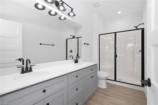 full bath featuring wood finished floors, a sink, toilet, and a shower stall