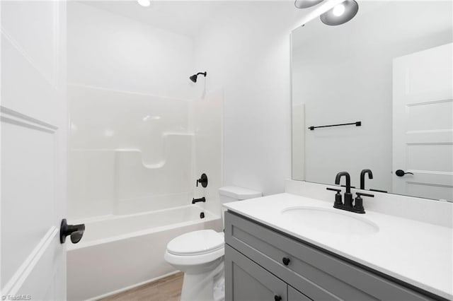 bathroom featuring toilet, shower / bathing tub combination, wood finished floors, and vanity