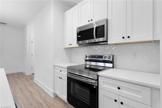 kitchen featuring decorative backsplash, light wood-style flooring, appliances with stainless steel finishes, light countertops, and white cabinetry