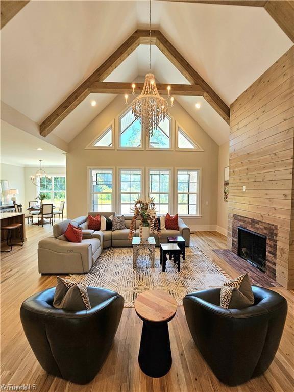 LOT121 N Holden Rd, Greensboro, NC 27410 - living room with a chandelier, high vaulted ceiling, light wood-type flooring, and a stone fireplace