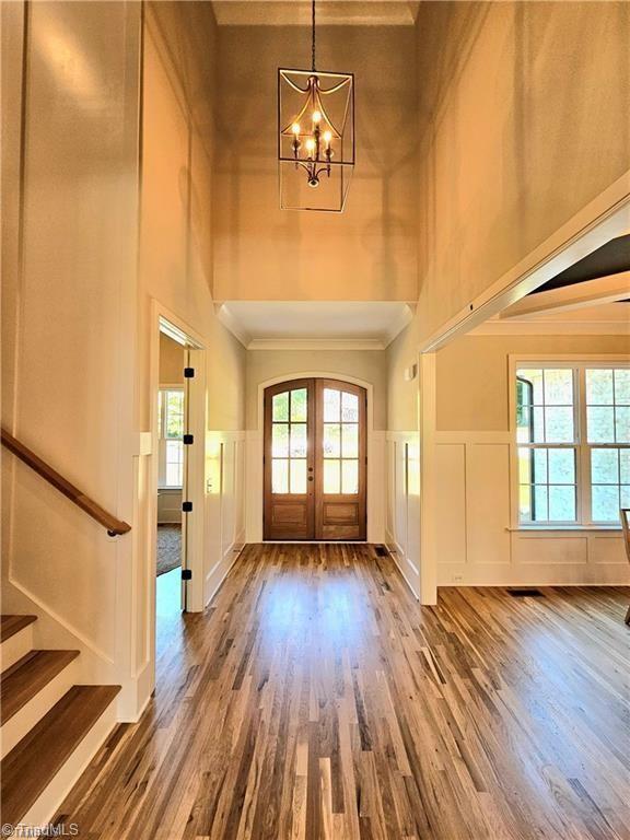LOT121 N Holden Rd, Greensboro, NC 27410 - entryway featuring a high ceiling, a decorative wall, wood finished floors, a chandelier, and a wainscoted wall