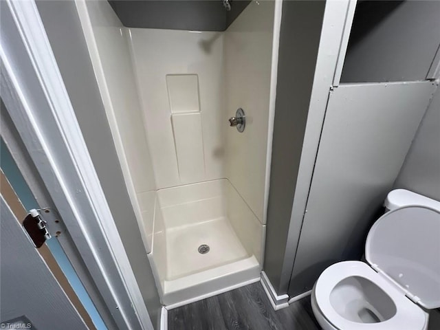 bathroom with hardwood / wood-style flooring, walk in shower, and toilet