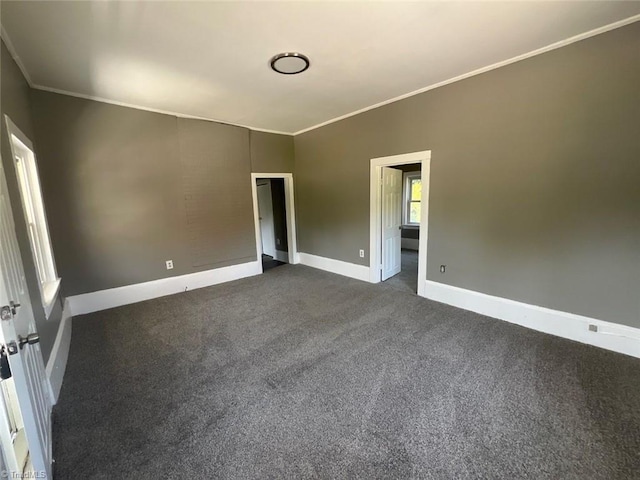 spare room featuring ornamental molding, dark carpet, and baseboards