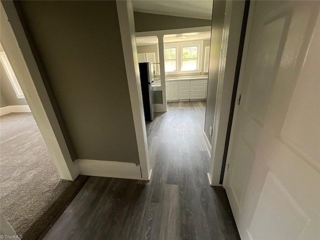 hallway featuring dark carpet and lofted ceiling