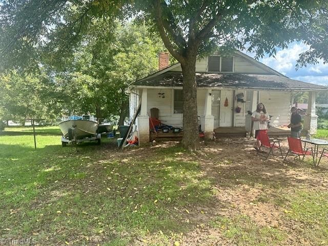 back of property with a porch and a lawn