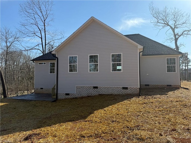 back of house with crawl space, a lawn, a patio, and roof with shingles