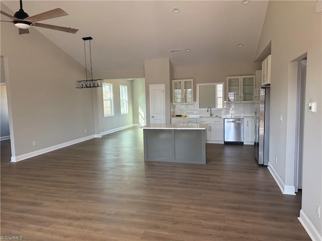 kitchen featuring open floor plan, appliances with stainless steel finishes, white cabinetry, and a sink