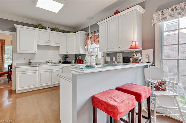 kitchen with a kitchen breakfast bar, kitchen peninsula, white cabinetry, and a healthy amount of sunlight