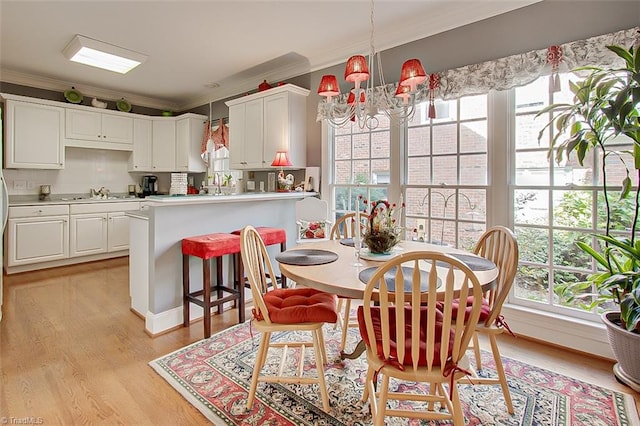 dining area with a notable chandelier, ornamental molding, and light wood-type flooring