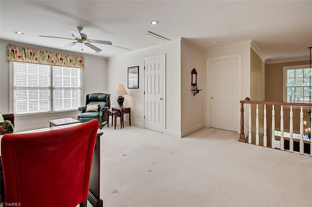 living area with ornamental molding, light colored carpet, and ceiling fan