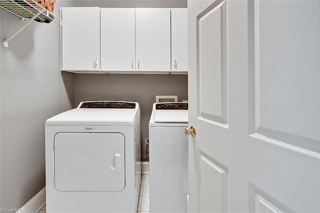 laundry area featuring washing machine and dryer, cabinets, and tile patterned flooring