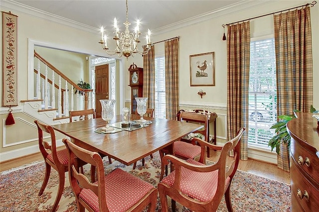 dining room with a notable chandelier, ornamental molding, and light wood-type flooring