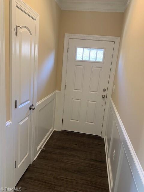 doorway to outside with dark wood-type flooring and crown molding