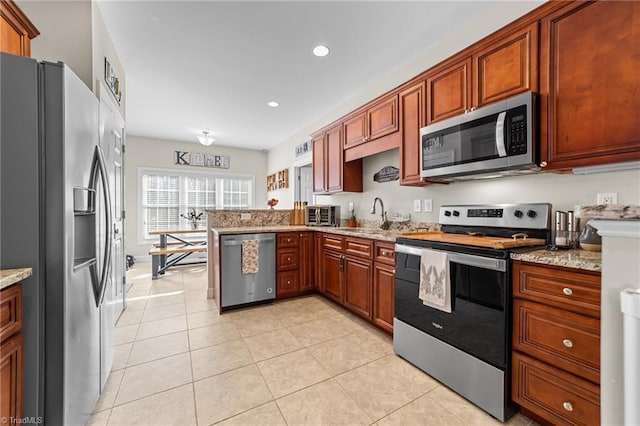 kitchen with sink, light tile patterned floors, light stone counters, kitchen peninsula, and stainless steel appliances