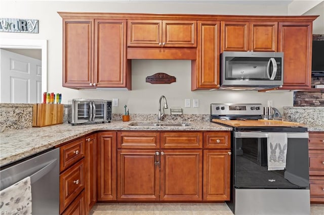 kitchen featuring stainless steel appliances, sink, and light stone counters