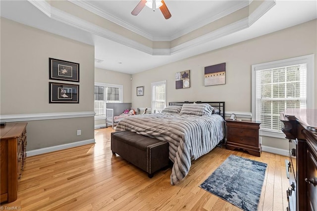 bedroom featuring crown molding, a tray ceiling, light hardwood / wood-style floors, and ceiling fan