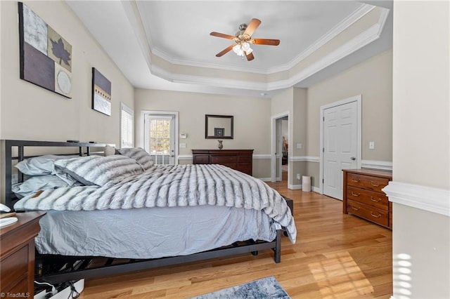 bedroom with crown molding, light hardwood / wood-style flooring, a raised ceiling, and ceiling fan