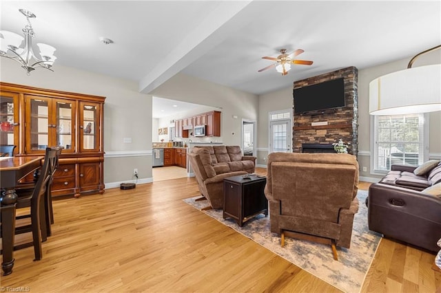 living room with a stone fireplace, light hardwood / wood-style floors, and a wealth of natural light