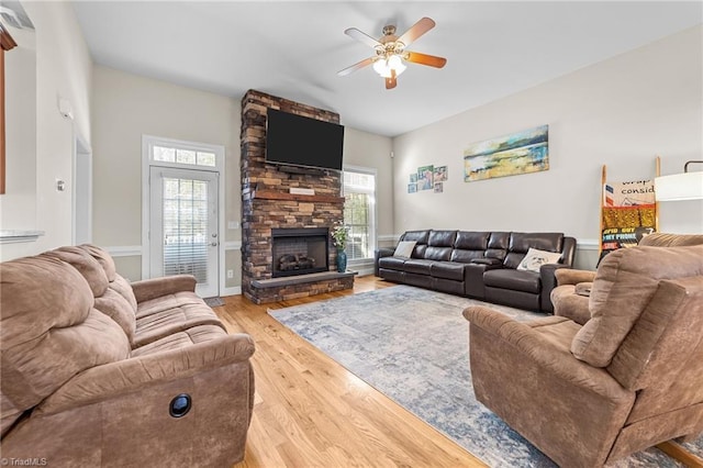 living room featuring a fireplace, ceiling fan, and light wood-type flooring