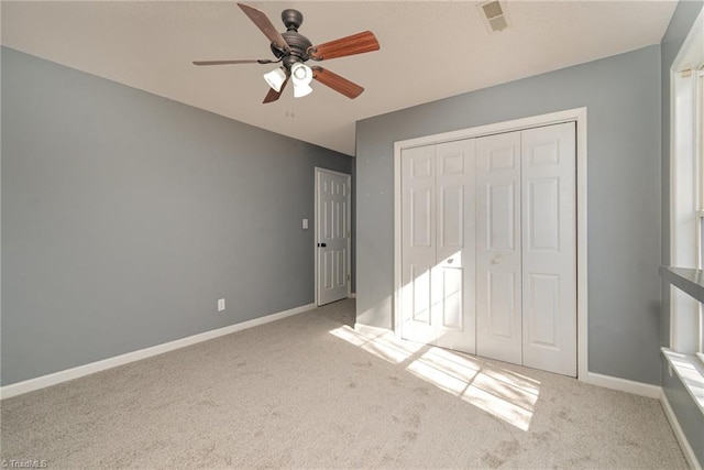 unfurnished bedroom featuring light colored carpet, ceiling fan, and a closet