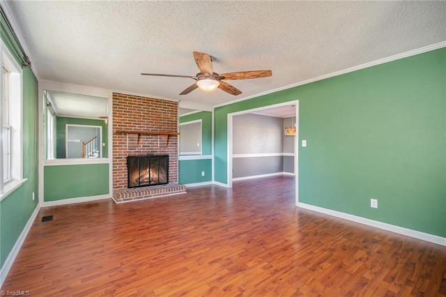 unfurnished living room featuring crown molding, wood-type flooring, a textured ceiling, ceiling fan, and a fireplace