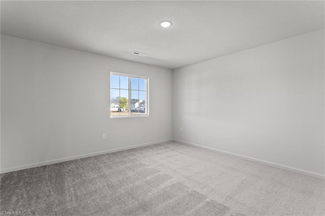 unfurnished room featuring carpet floors, visible vents, a textured ceiling, and baseboards